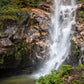 Waterfall cascading down a rocky cliff with greenery