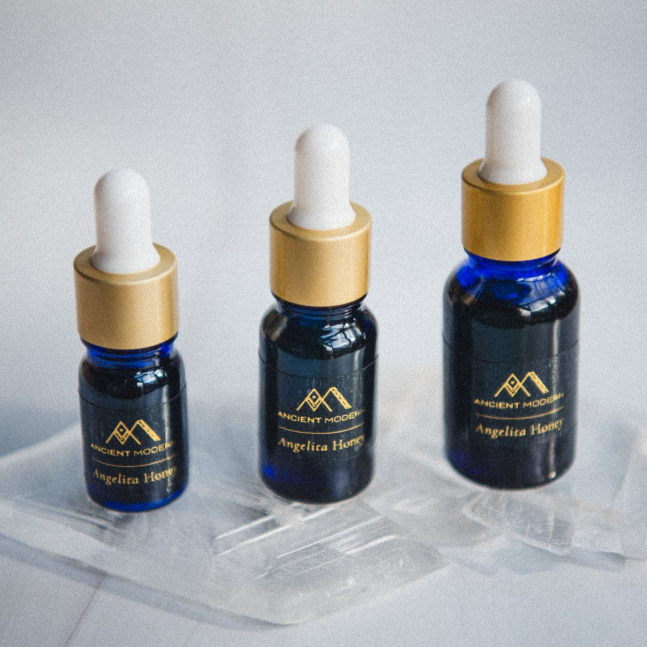 Three dropper bottles with liquid angelita honey on a white background