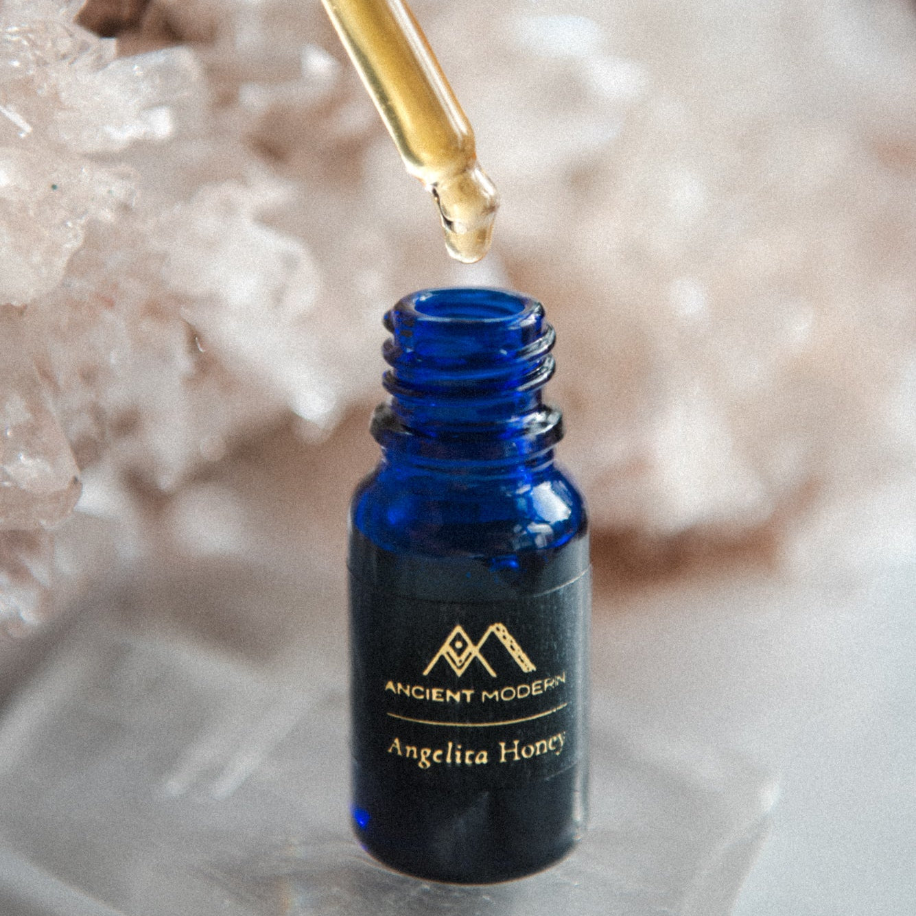 Blue bottle of Angelita Honey with a dropper over crystal rock background