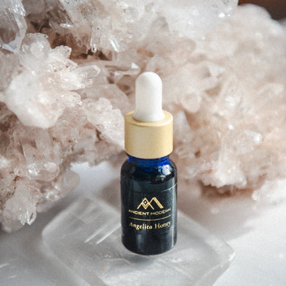 Bottle of Angelita Honey with dropper on a crystal surface