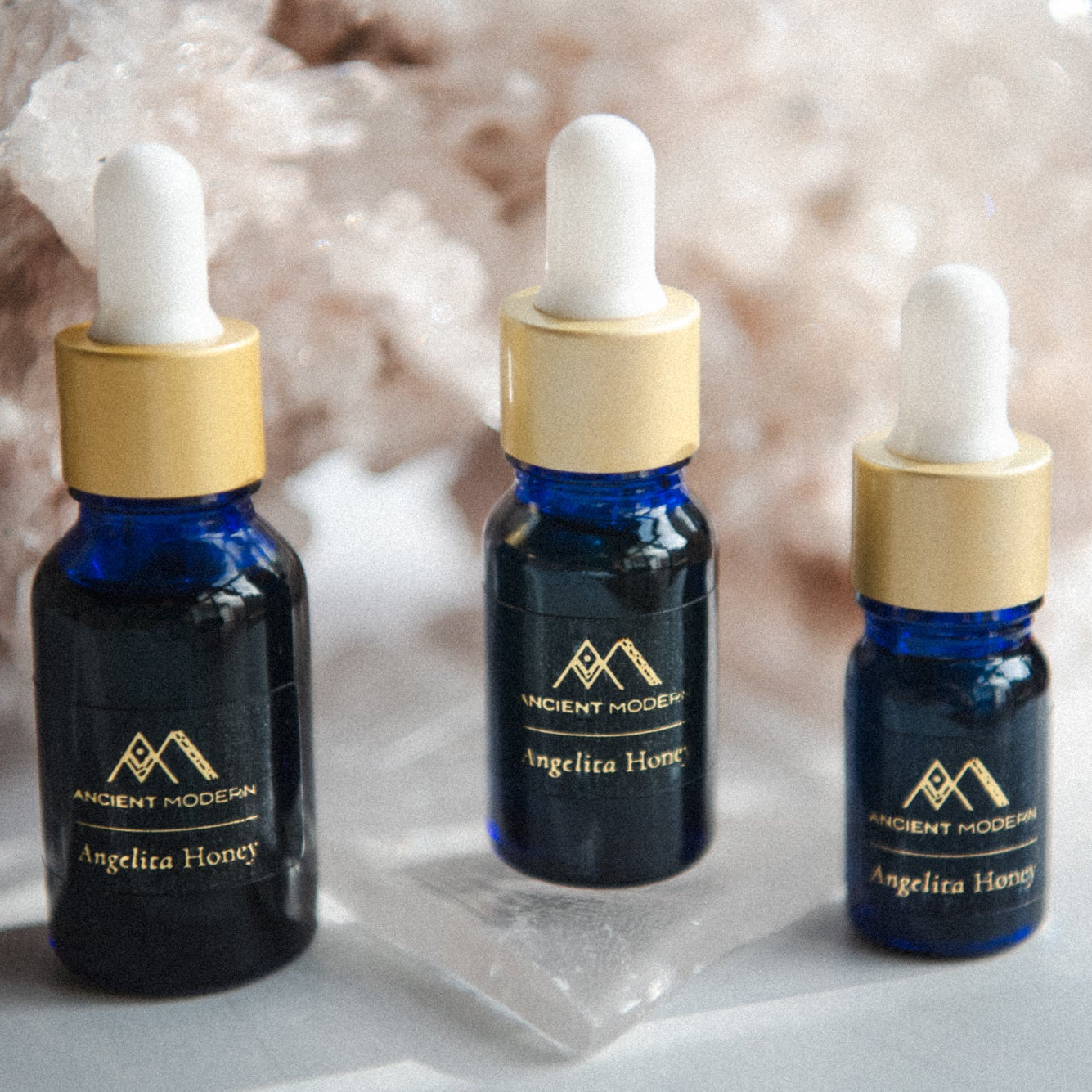 Three dropper bottles with Angelita Honey on a textured surface